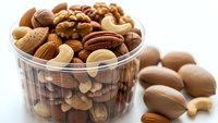 Mixed nuts assortment in glass bowl with almonds, walnuts, cashews, pecans and hazelnuts for healthy snacking and cooking recipes.