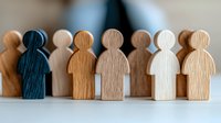Wooden figures standing in row symbolizing diversity, inclusion and teamwork concept. Close up view of minimalist wooden toys on light background.