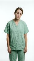 Middle-aged woman with light skin tone wearing green medical scrubs, standing against white background. Healthcare worker portrait for medical, nursing, and hospital-related projects.