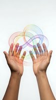 Hands of a dark-skinned person holding a glowing rainbow infinity loop, symbolizing creativity, diversity, and endless possibilities on white background.