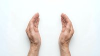 Two elderly hands positioned protectively facing each other on white background, symbolizing care, protection, and security concepts for healthcare design.