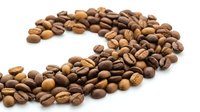 Fresh roasted coffee beans scattered on white background forming curved line pattern for cafe menu design and beverage advertising materials.