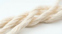Twisted natural fiber rope in cream and beige tones, showcasing detailed texture and braided construction for nautical, craft, and industrial design projects.