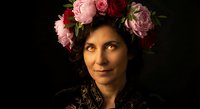 Middle-aged woman with floral crown of pink and red roses against dark background, portrait photography for fashion, beauty and lifestyle projects.