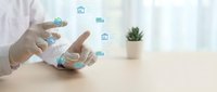 Professional using smartphone with floating digital real estate icons for property management and investment applications on modern desk.