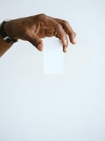 Male hand with dark skin tone holding blank white business card against neutral background for branding and corporate identity mockup purposes.