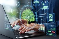 Hands typing on laptop with holographic green tree and digital interface icons representing sustainable technology and environmental business solutions.