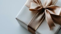 Elegant gift box wrapped in silver paper with luxurious champagne satin ribbon bow on neutral background, perfect for special occasions and celebrations.