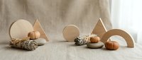 Natural wooden geometric shapes and acorns arranged on neutral linen fabric creating minimalist autumn composition for home decor and craft projects.