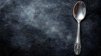 Elegant vintage silver spoon with ornate handle on dark textured background for culinary and kitchen design projects.