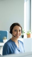 Smiling female customer service representative wearing headset in modern office environment for business communication and support services.