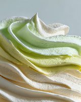 Swirled layers of colorful meringue in pastel green, yellow and white tones, creating a soft textured dessert background for food photography.