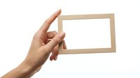 Hand holding empty wooden photo frame on white background for mockup design and presentation purposes.