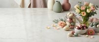 Easter spring composition with pastel colored eggs, fresh roses and eucalyptus branches on white marble surface for holiday greeting cards and decorations.