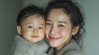 Happy Asian mother embracing adorable baby son in cozy knit sweater showing maternal love and family bonding moments at home.