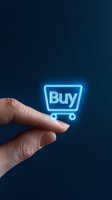 Glowing neon blue shopping cart icon with buy text balanced on fingertip against dark background, representing online shopping and e-commerce concept.