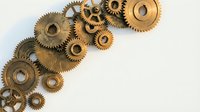 Vintage brass mechanical gears and cogs arranged on white background for steampunk industrial design projects and engineering concepts.