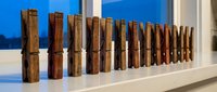 Row of wooden clothespins lined up on white windowsill with blue sky background, natural lighting for laundry and household organization concepts.