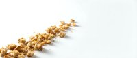 Popcorn kernels scattered in diagonal line on white background, isolated and ready for design use on packaging, marketing materials, and food-related projects.