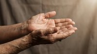 Elderly hands cupped together in receiving gesture showing wrinkled skin and life experience against soft neutral background for care concepts.