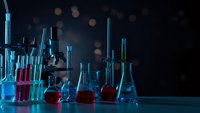 Laboratory glassware with colorful chemical solutions on dark background with bokeh lights for scientific research and experimentation.