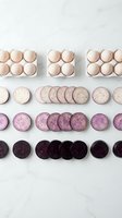 Organic eggs and sliced purple potatoes arranged in gradient rows on white marble surface for healthy cooking and farm fresh ingredient concepts.