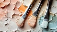 Professional artist paintbrushes with natural bristles on palette with dried acrylic paint chips in pastel colors for creative artwork and painting projects.