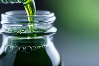 Fresh green juice pouring into glass jar with bubbles and foam, healthy detox smoothie drink for wellness and nutrition lifestyle.