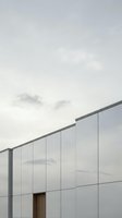 Modern building facade with translucent panels and metal framework against overcast sky. Minimalist architectural design suitable for corporate, real estate, and contemporary construction projects.