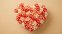 Heart-shaped arrangement of pink and coral carnation flowers on beige background for Valentine's Day, Mother's Day, wedding, anniversary celebration.