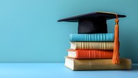 Stack of colorful academic books with black graduation mortarboard cap and orange tassel on blue background, symbolizing educational achievement and academic success.