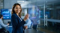 Professional Asian businesswoman interacting with futuristic holographic interface in modern office environment for technology presentations.