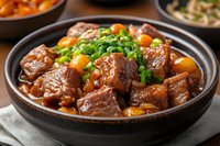 Tender braised beef chunks with potatoes and carrots in rich brown sauce, garnished with fresh chopped green onions, served in traditional ceramic bowl.