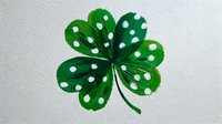Green shamrock with white polka dots on textured paper background, symbol of Irish luck and St. Patrick's Day celebrations.