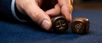 Professional hands holding wooden dice with justice scales and gender symbols representing legal equality and civil rights concepts in courtroom setting.