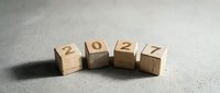 Wooden blocks displaying 2027 numbers arranged in row on concrete surface for new year planning and goal setting concepts.