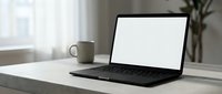Modern laptop with blank white screen on minimalist desk workspace with coffee cup and plant for mockup presentations and digital design projects.
