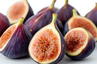 Fresh ripe purple figs cut in half showing juicy pink flesh and seeds on white background, macro food photography for healthy eating concept.