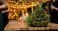 Fresh green herbs bundled with twine on rustic wooden table with golden bokeh lights and people celebrating in background for culinary cooking.