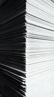 Stack of white paper sheets with black edges showing thickness and layers for office and business documentation needs.