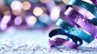 Curled sparkly ribbons in purple and turquoise with glitter texture against blurred bokeh background create festive holiday atmosphere for celebration designs.