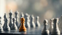 Single wooden chess pawn stands out among blurred white and black pieces on board, symbolizing leadership, strategy, and individual success in business.