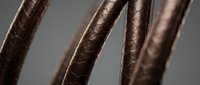 Close-up of brown leather cords with detailed texture showing natural grain patterns and craftsmanship for fashion accessories and jewelry making projects.