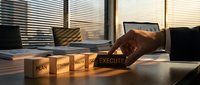 Businessman arranging wooden blocks with business strategy steps plan strategy analyze focus execute on office desk in warm sunset light.