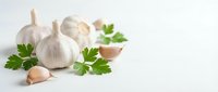 Fresh garlic bulbs and cloves with green parsley leaves on white background for culinary cooking and healthy food preparation.