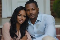 Young African American couple in casual elegant attire sharing intimate moment outdoors. Woman in pink blouse with long dark hair and man in light blue shirt pose together.