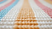 Macro view of colorful striped knitted fabric texture showing detailed yarn pattern in pastel pink, blue, orange and white. Soft textile background for design projects.