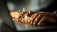 Hands typing on laptop keyboard with glowing digital icons floating above, representing online connectivity, digital communication and modern technology workflow.