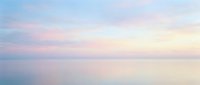 Serene dawn seascape with soft pastel pink and blue hues reflecting on calm water, perfect for peaceful backgrounds and wellness designs.