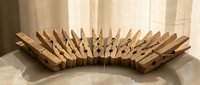 Wooden clothespins arranged in curved wave pattern on white surface creating abstract sculptural form for creative design projects.